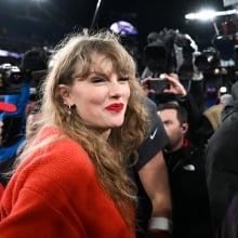 Taylor Swift in a red sweater on the field celebrating the Kansas City Cheifs' win.