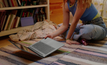 a close-up of a woman picking up an hp chromebook plus 15.6-inch off the floor