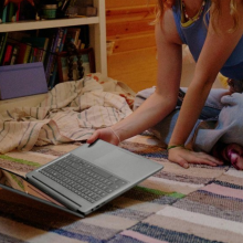 a close-up of a woman picking up an hp chromebook plus 15.6-inch off the floor