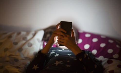 A child looks at online content while in bed.