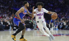  Jeff Dowtin Jr. #11 of the Philadelphia 76ers dribbles the ball to the basket against Cameron Payne #1 of the New York Knicks in the first half at the Wells Fargo Center on January 15, 2025 in Philadelphia, Pennsylvania. 