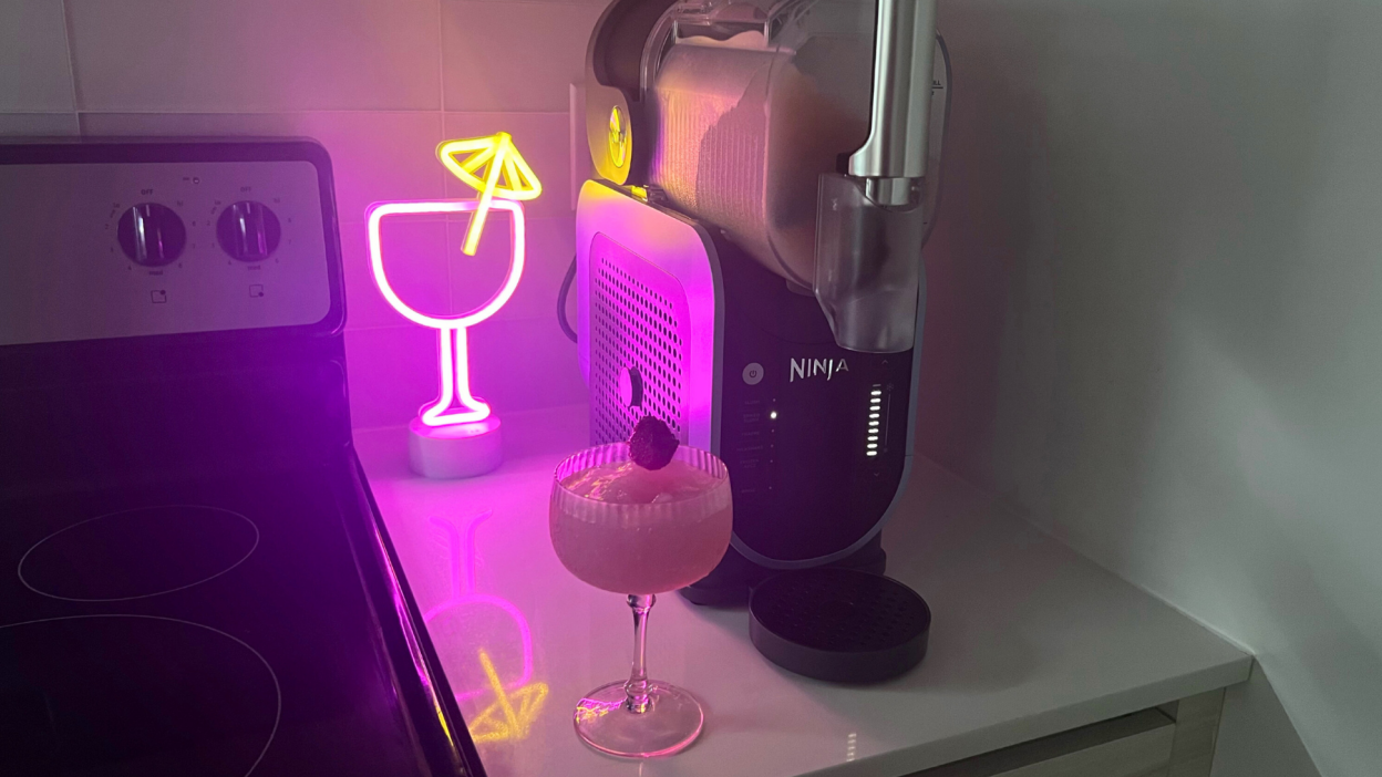 Ninja Slushi frozen drink maker. margarita glass, and neon light decoration sitting on countertop