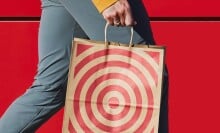 a person holding a brown paper target bag with the red target image on the front