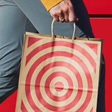 a person holding a brown paper target bag with the red target image on the front