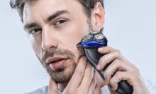 Person using blue and black beard trimmer on facial hair