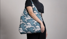 Person in all black holding a blue and white bag with a wave pattern