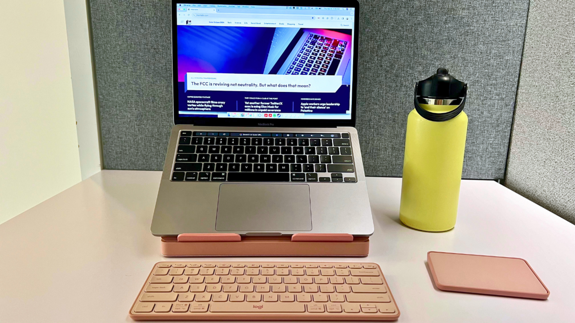 pink logitech keyboard and trackpad with laptop sitting on stand