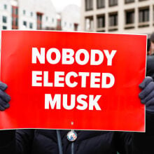 Someone holding a sign that says "NOBODY ELECTED MUSK" at an anti-DOGE protest