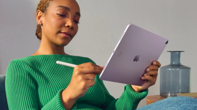 Person writing with Apple Pencil on purple iPad Air