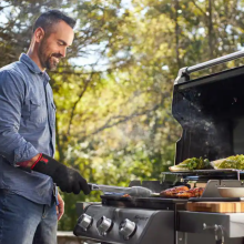 A man cooks out on a Weber grill