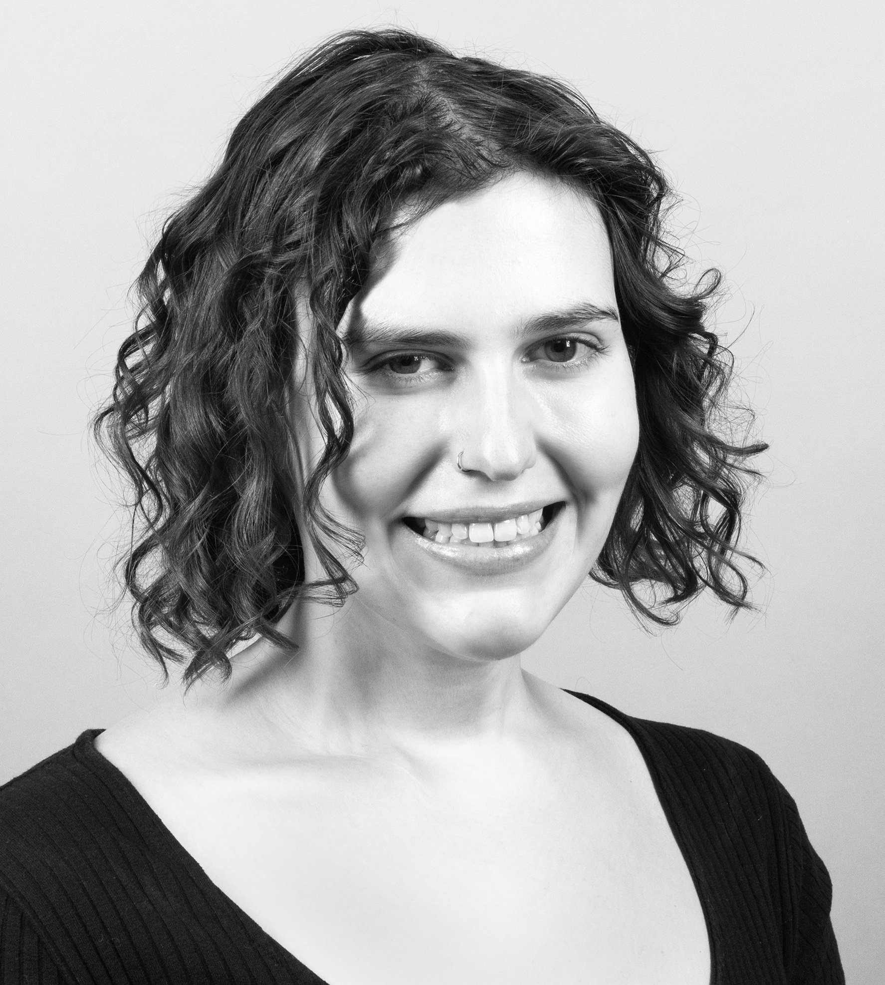 anna iovine, a white woman with curly chin-length brown hair, smiles at the camera