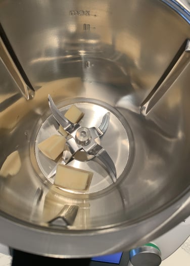 hunks of Parmesan cheese in bowl with blades