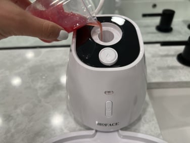 hand pouring red liquid into top of bioface machine