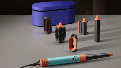 Dyson Airwrap in turquoise and orange laying beside attachments and carrying case