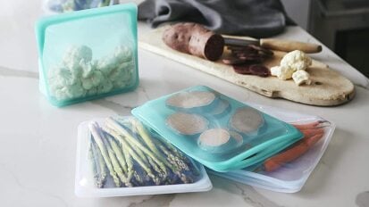 a pile of multicolored stasher reusable storage bags filled with chopped vegetables