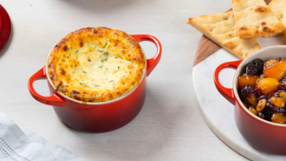 a close-up of two le creuset mini round cocottes filled with a pot pie and a fruit cobbler next to a plate of pita pieces