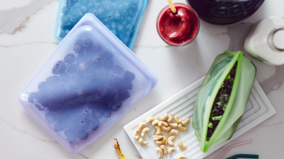 a top-down view of stasher bags filled with berries and vegetables on a marble countertop