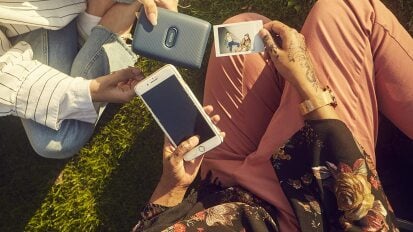 two people looking at pictures printed from a fujifilm Instax Mini Link 