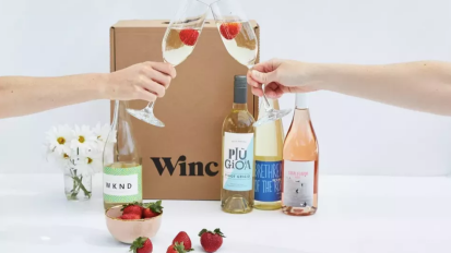 winc box with wine bottles and people clinking full wine glasses 