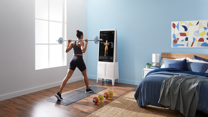 Woman lifting a barbell in front of a Tempo system.