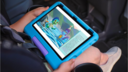 a child reading an e-book on a Amazon Fire HD 10 Kids tablet while sitting in a car seat