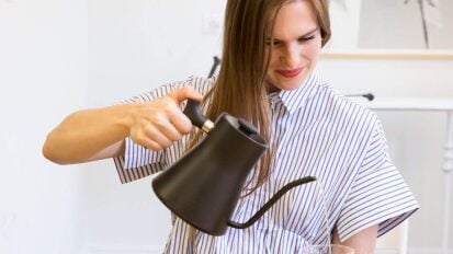 A person using an electric kettle to make a cup of tea.