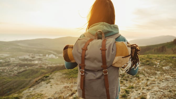 woman with backpack looks at the sunset