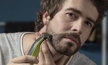 Person using a Philips Norelco OneBlade electric razor to shave.