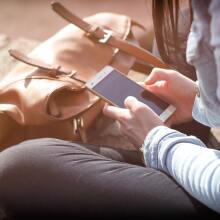 a close-up of a sitting woman typing on a smartphone