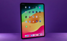 An iPad Pro standing against a purple background.