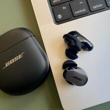 bose quietcomfort ultra earbuds on table next to macbook