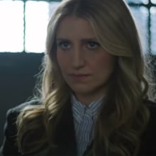 A woman stands in a dark prison visiting room.