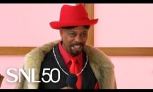 black man in black fur suit with red dress shirt and red fedora hat