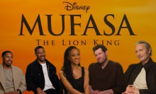 Left to right:  Kelvin Harrison Jnr, Aaron Pierre, , Tiffany Boone, Billy Eichner, and Mads Mikkelsen sit against an orange "Mufasa" backdrop