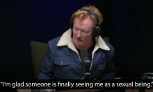 A man sits at a table wearing headphones in a podcast studio. The caption at the bottom reads, "I'm glad someone is finally seeing me as a sexual being."