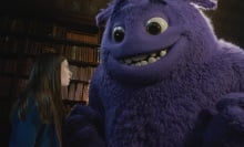 A large, fluffy, purple creature smiles at a young girl.