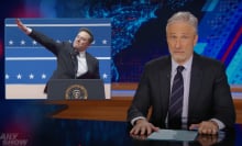 A man sits in front of a talk show desk. In the top-left is an image of another man appearing to give a Nazi salute.