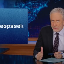 A man sits behind a talk show desk looking angry. In the top left is the logo for DeepSeek AI.