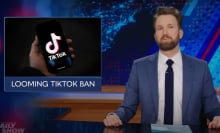 A man sits behind a talk show desk with an image of the TikTok logo on the left.