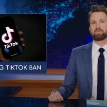 A man sits behind a talk show desk with an image of the TikTok logo on the left.