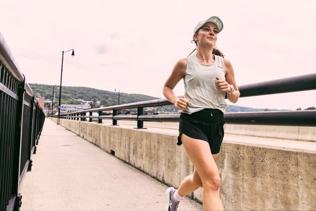 Woman jogging along a walkway with a scenic view of hills and a cloudy sky. Woman jogging along a walkway with a scenic view of hills and a cloudy sky.