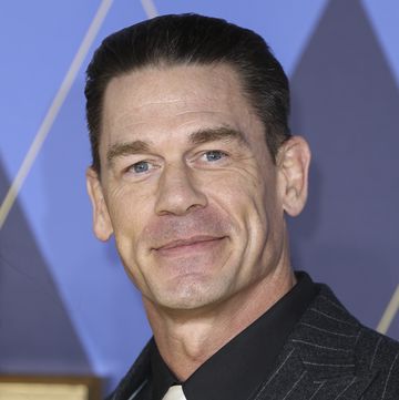 john cena wearing a suit and tie and smiling at the camera