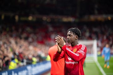 kobbie mainoo applauds manchester united fans as he walks along the side of the pitch after a football match