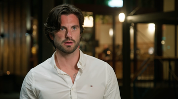 married at first sight star eliot wearing a white shirt standing in a restaurant