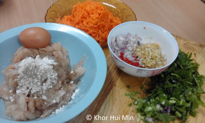 Ingredients for Chicken & Carrot Burger Patty. Clockwise from top: A whole grated carrot, Chopped onion, finely chopped red chilli (seeds removed), finely chopped lemongrass, chopped spring onions, chopped fresh coriander leaves, 1 & a half chicken breasts (minced or chopped) seasoned with corn flour, black pepper, salt, and lastly, an egg.