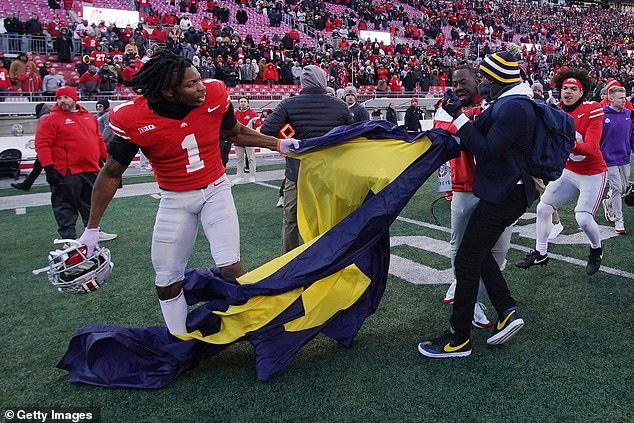 Davison Igbinosun of the Ohio State Buckeyes grabs a Michigan flag following his team's defeat