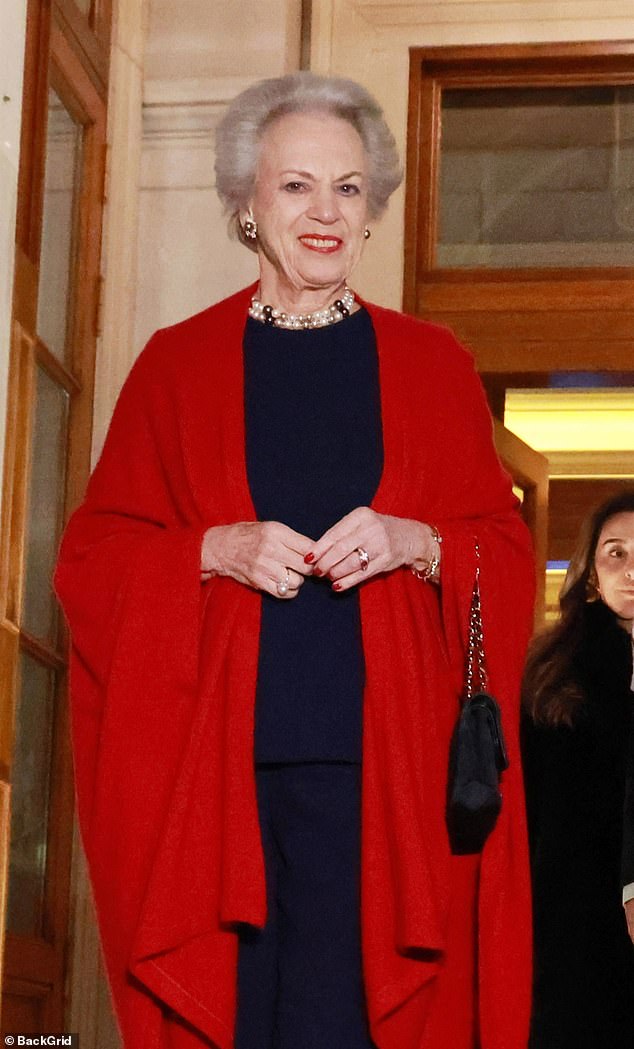 The royal, 80, looked sensational in a chic red cape over a monochrome blue outfit which included a high-collared top and a pair of tailored trousers