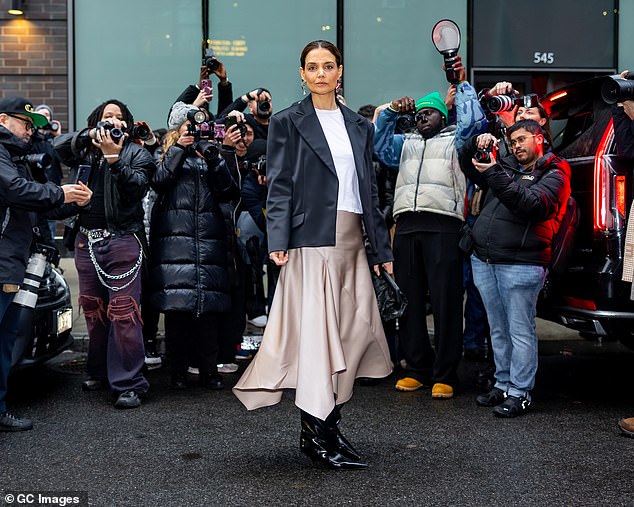 Katie stood tall in shiny black boots with pointy toes