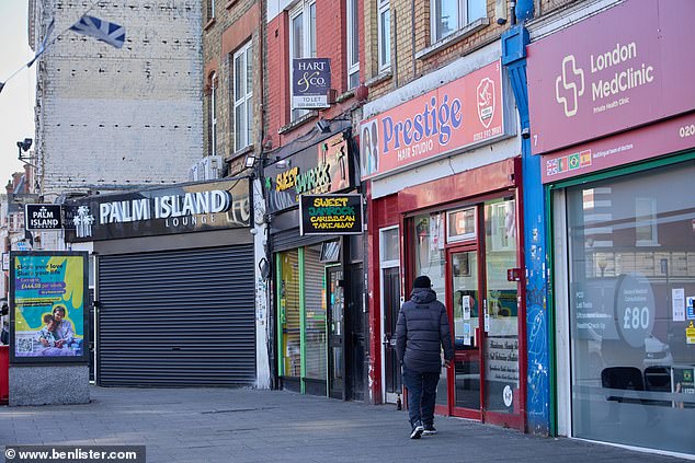 A row of shop fronts, including a hair studio, a health clinic and a Caribbean takeaway