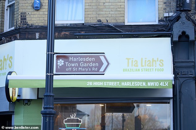 A sign pointing to Harlesden Town Garden off St Mary's Road outside a Brazilian street food restaurant